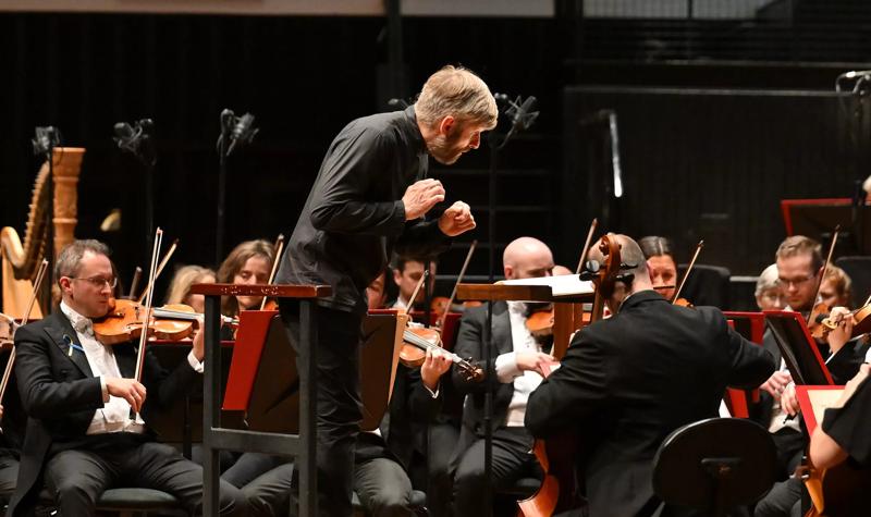Conductor Kirill Karabits leaning over a cello player