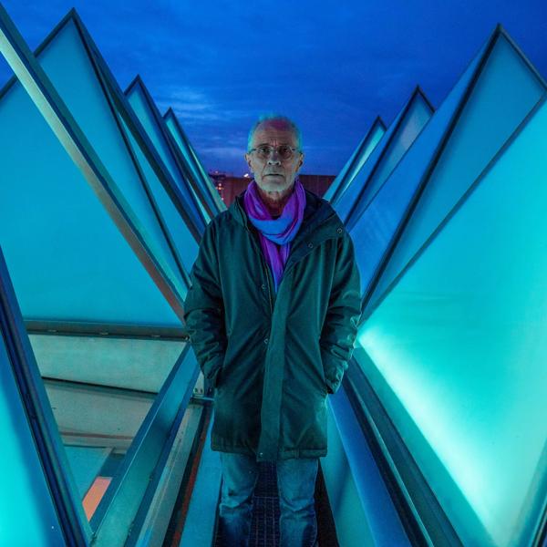 Artist David Batchelor stands on the roof of the Hayward Gallery between the pyramid windows, illuminated by his installation piece Sixty Minute Spectrum
