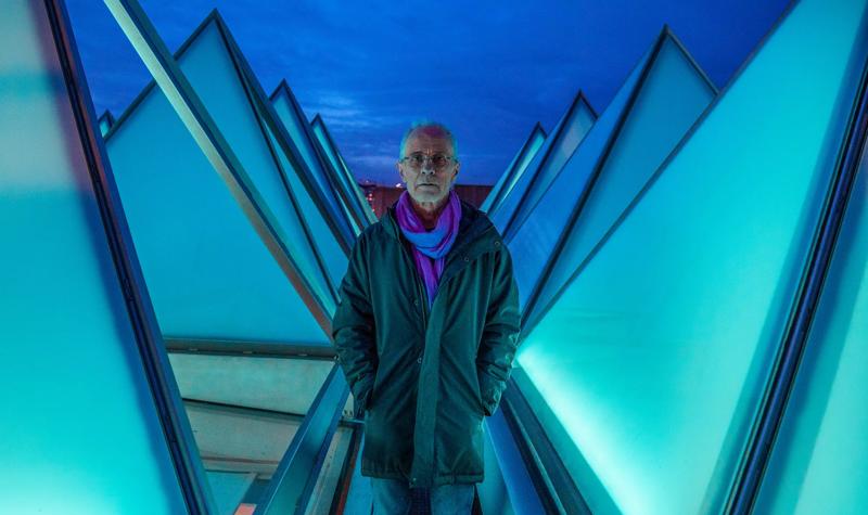 Artist David Batchelor stands on the roof of the Hayward Gallery between the pyramid windows, illuminated by his installation piece Sixty Minute Spectrum
