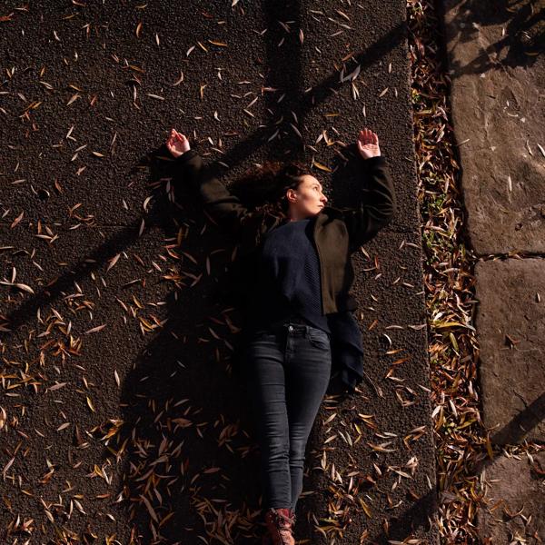 A person lying on the streets over an Autumn leaves