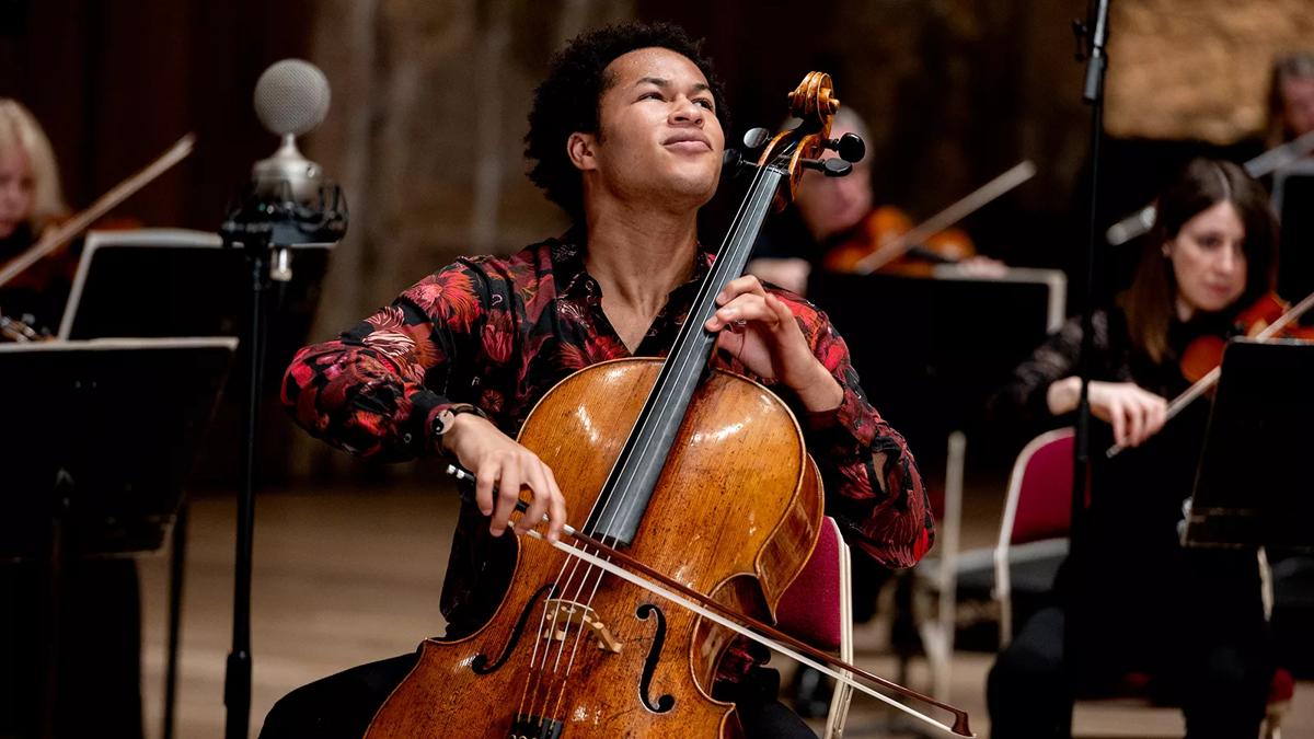 Cellist Sheku Kenneh-Mason in a red floral shirt playing passionately 