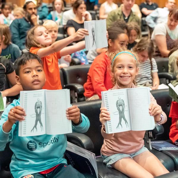 Children holding up open books in the Purcell Room