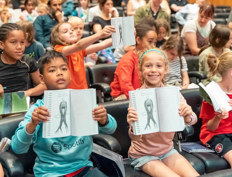 Children holding up open books in the Purcell Room