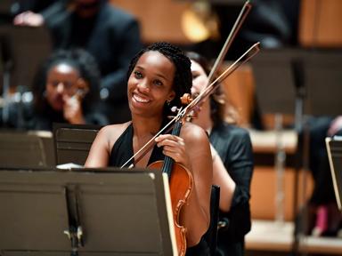 A violinist smiling at the Chineke! Orchestra: Symphonic Celebration