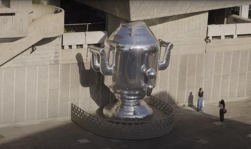 A woman stands for her friend to take a photo of her behind the large-scale installation Samovar at Hayward Gallery