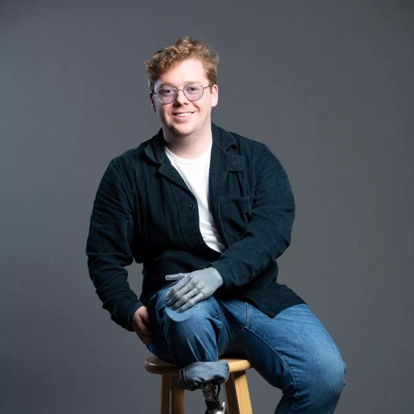 An image of Patrick Kane sitting on a stool. He has a bionic left arm and a prosthetic right leg