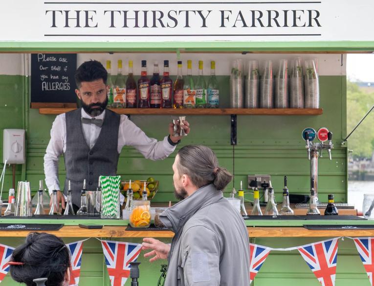 A bartender making a cocktail in a green truck
