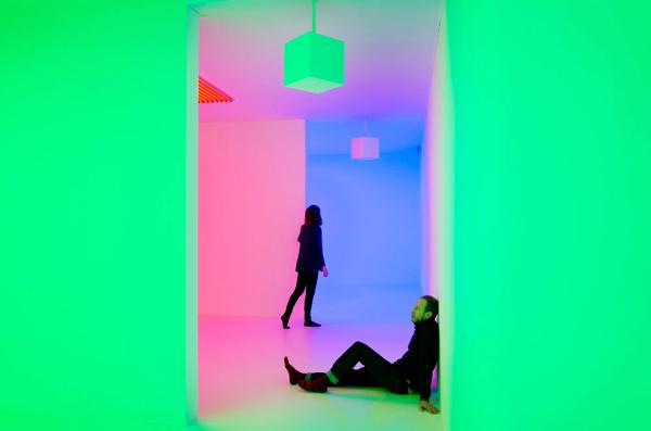 Visitors sitting and standing in Green and Pink Light Installation by artist, Carlos Cruz-Diez at Hayward Gallery