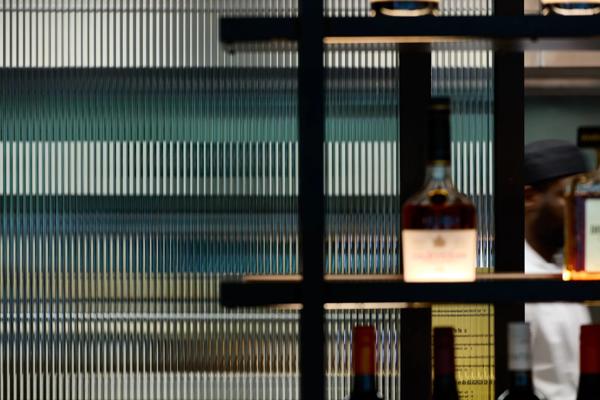 Fluted glass panel behind the bar with out of focus bottles of alcohol in the foreground