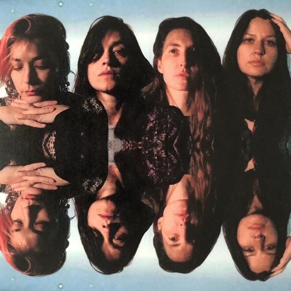 Photo of all 4 members of Warpaint. Their heads are reflected beneath them. 