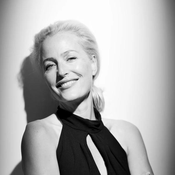 Gillian Anderson wears a black dress in a black and white photo