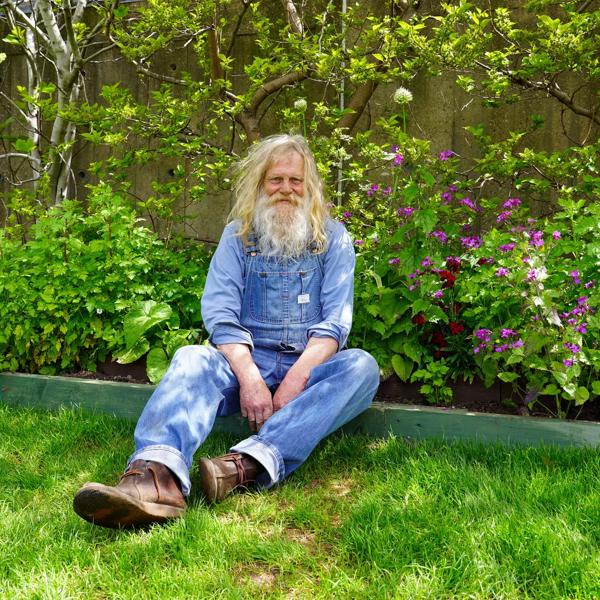 Paul Pulford, man sitting on the floor of the garden lawn, smiling