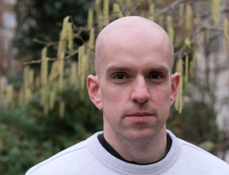 A man wearing a white sweatshirt in a garden