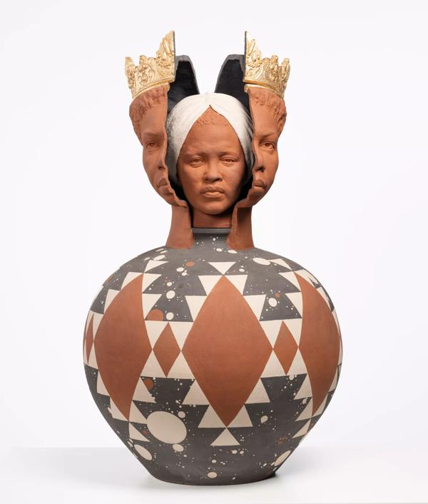 A ceramic pottery vase with a woman's head inside a split woman's face