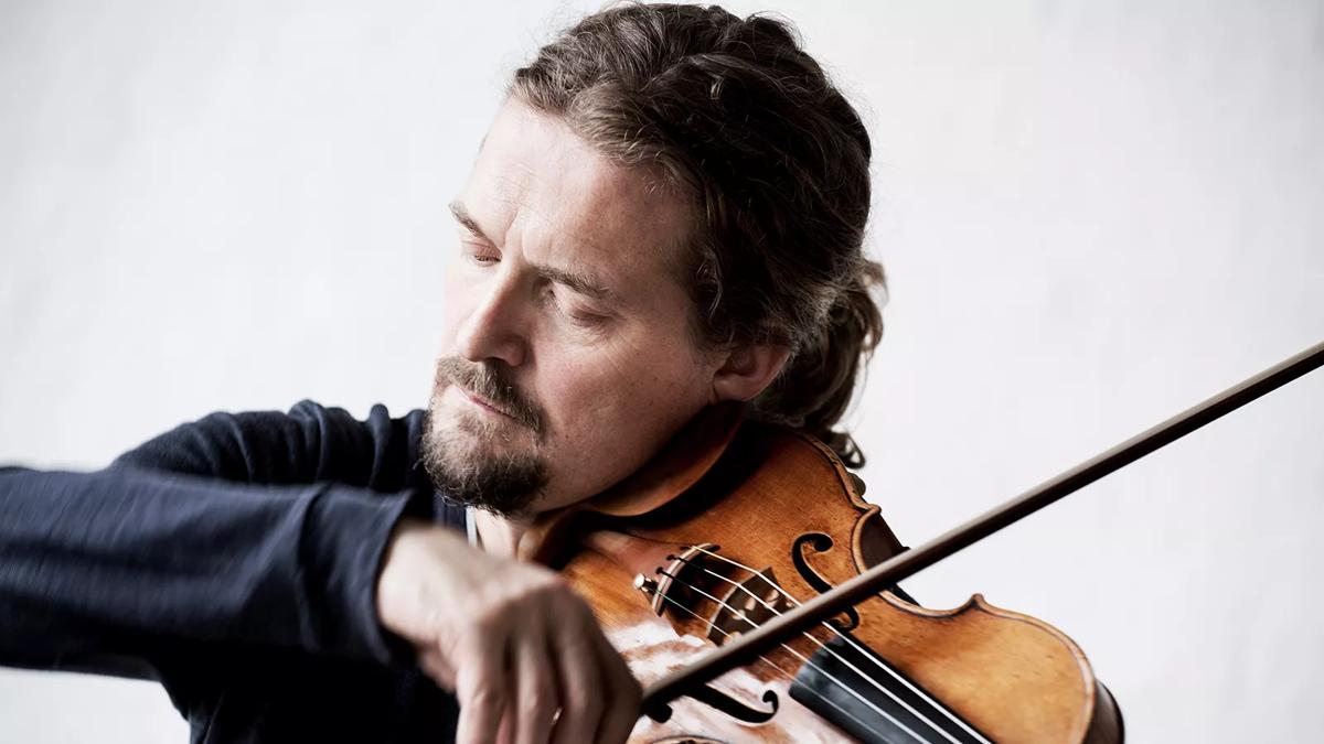 Violinist Christian Tetzlaff pictured with a violin by a white backdrop