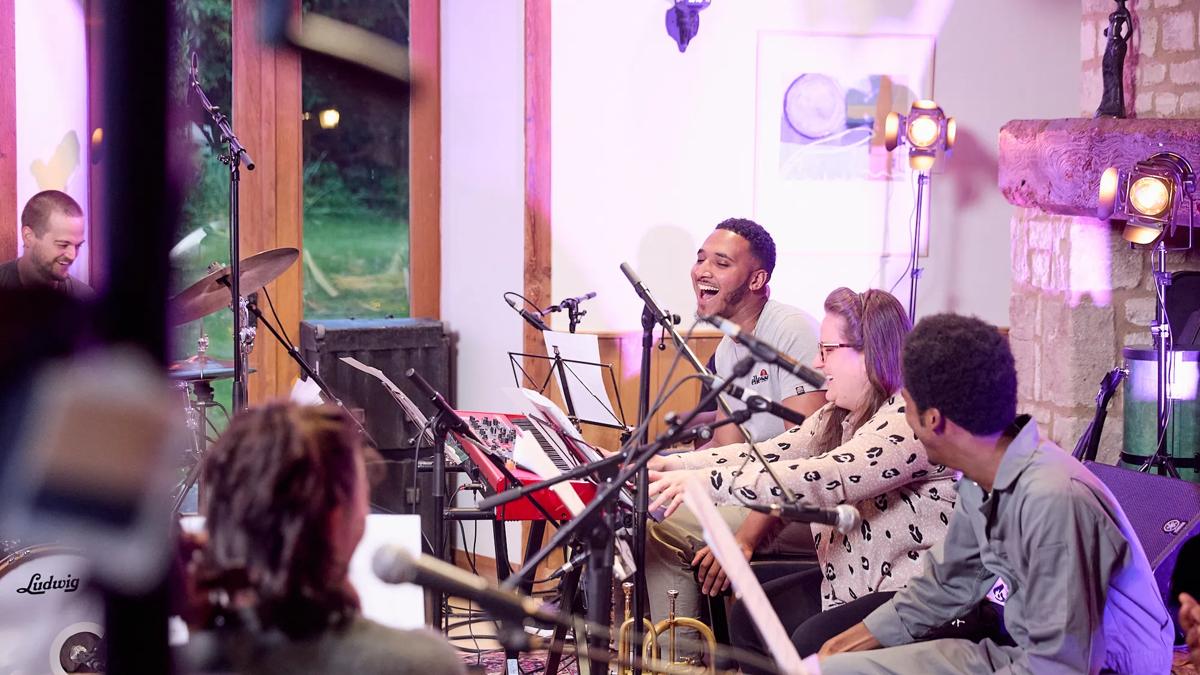 Jazz musicians playing instruments in a house, they are all laughing.