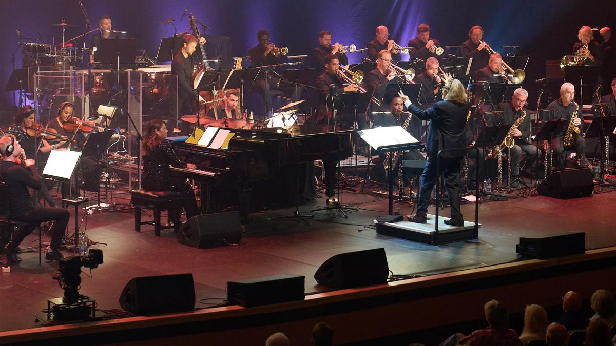 A jazz orchestra on stage with a conductor at the front