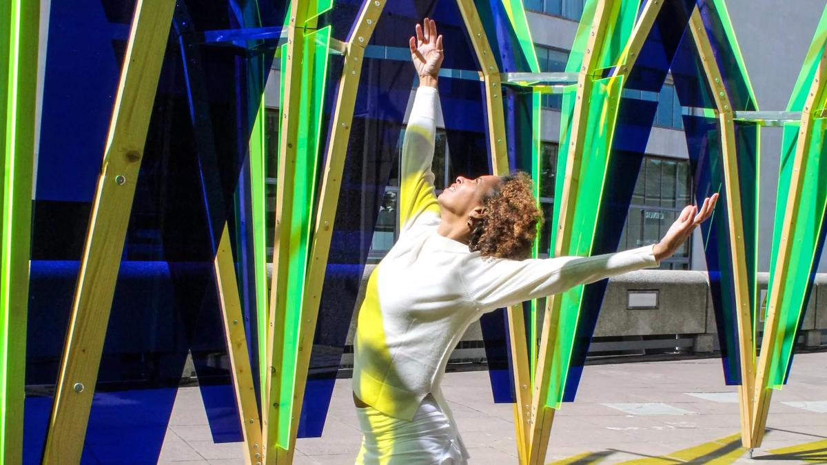 A performer dancing in The Hop pavilion, a large geometric structure