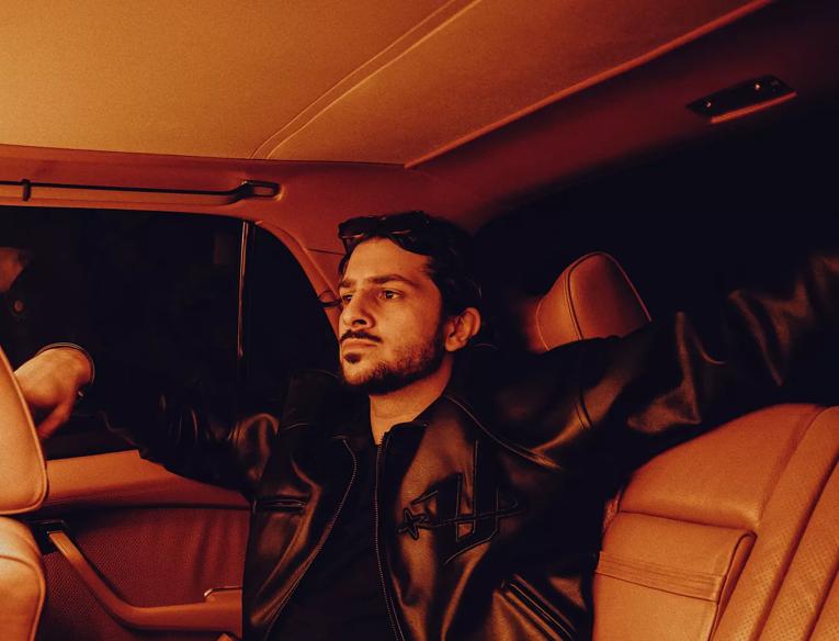 A man wearing a leather jacket sat in a car 