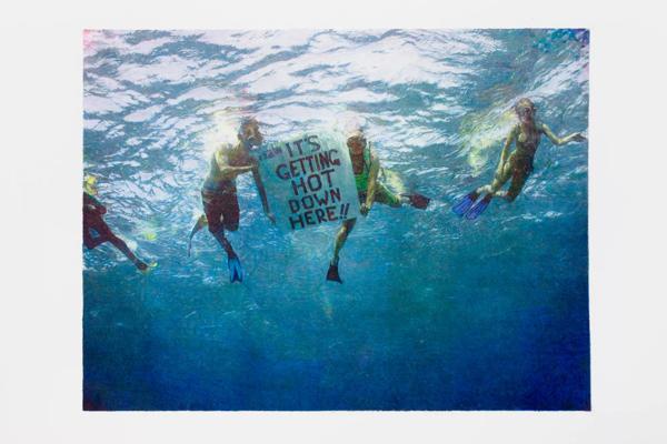 Scuba diving activists holding  a poster sign under the sea 'IT"S GETTING HOT DOWN HERE!!' 