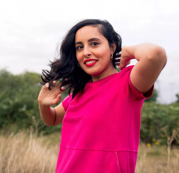 Writer Sharan Hunjan wears a pink dress in a field
