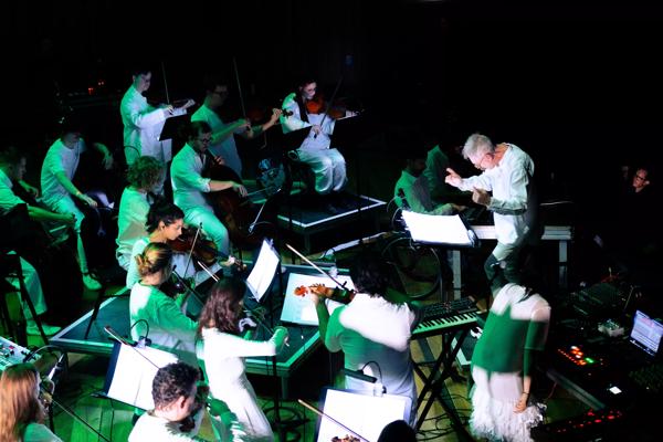 Paraorchestra: Trip the Light Fantastic at the Bristol Beacon. A view of the orchestra from above bathed in green light.