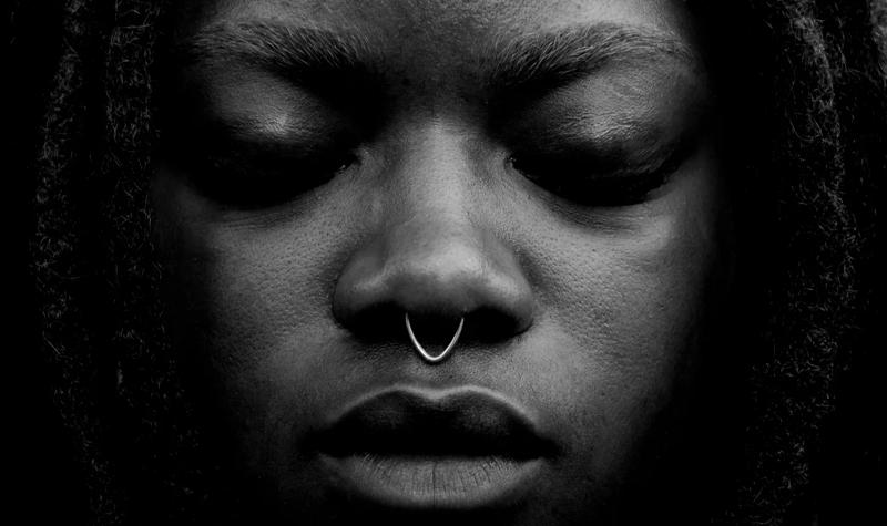  A close-up black and white shot of a woman's face with a nose ring