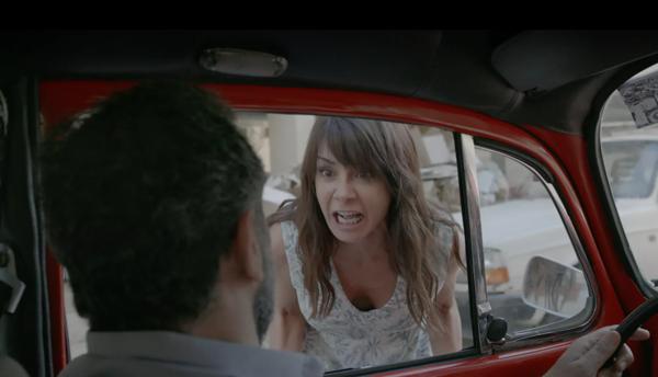 A woman shouting at a man in a red car