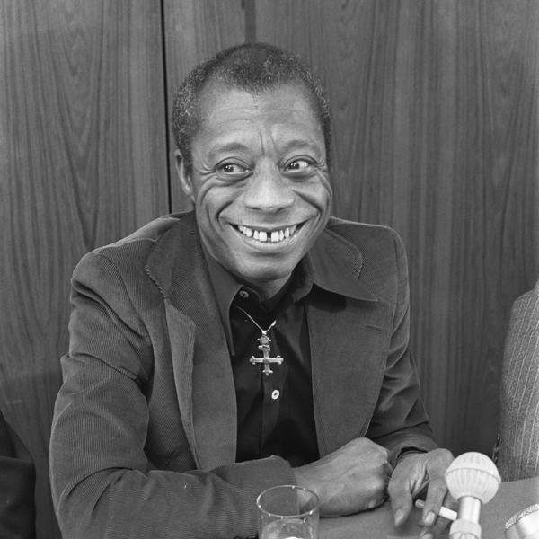 Black and white image of James Baldwin holding a cigarette.