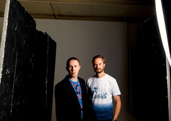 Ant Law on the left wearing a t-shirt & Alex Hitchcock o the right wearing a black blazer over a t-shirt. 