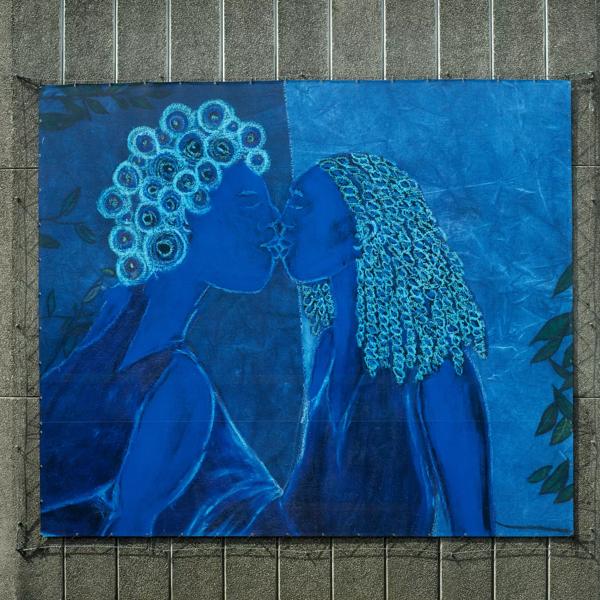 A mixed media painting on a blue canvas. Two women are kissing. Their skin is bright blue, they have blue hair and clothing.