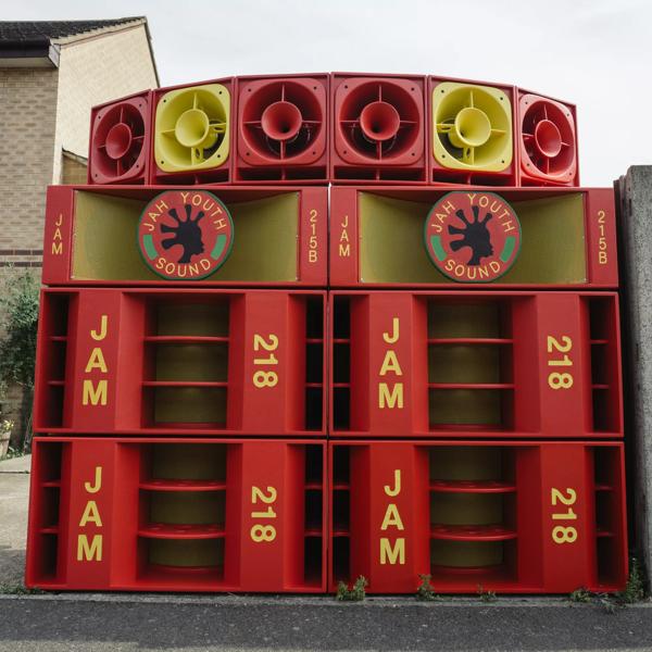 Large red and yellow sound system outside with Jay Youth Sound's logo on the centre of the second to top speakers.