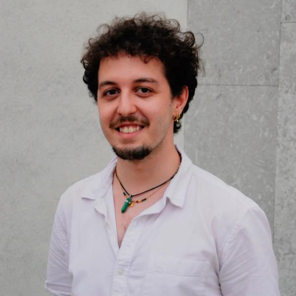 Raphael Nemes, a young White man with short dark hair a goatee beard and moustache wearing a white shirt