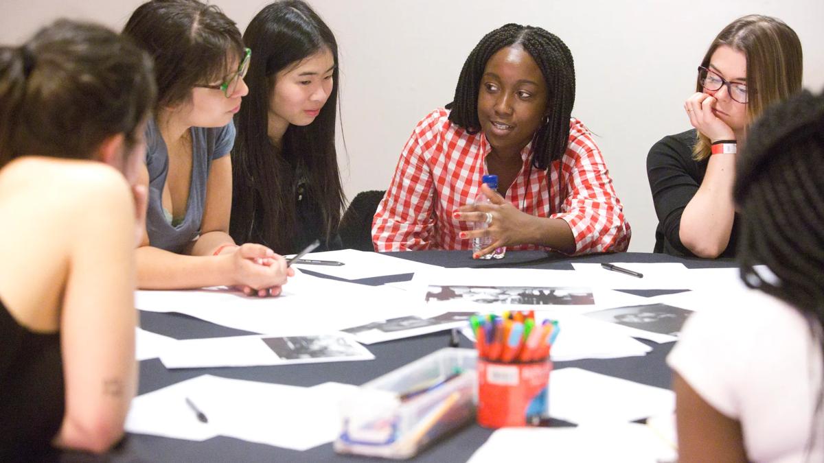 A group of people sat around a table, looking at pieces of paper