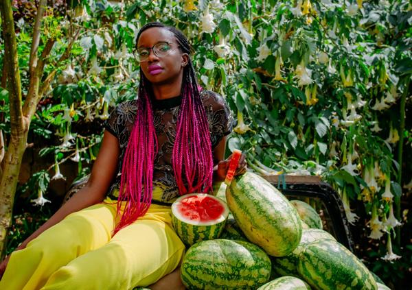 A musician sporting pink braids and eating watermelon