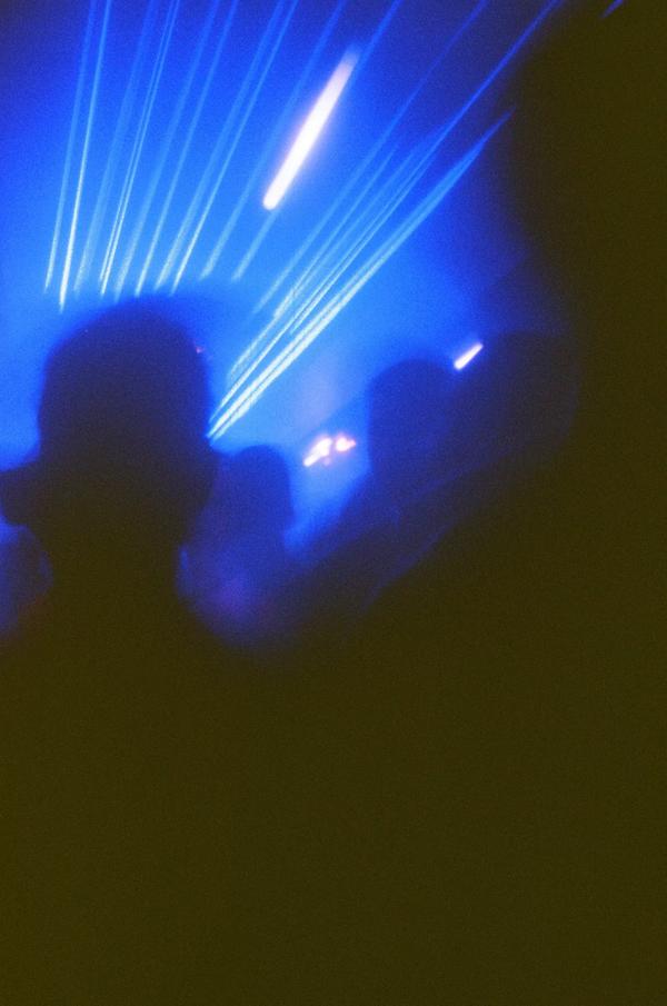 Dark club scene with blue lighting and silhouettes of people dancing.