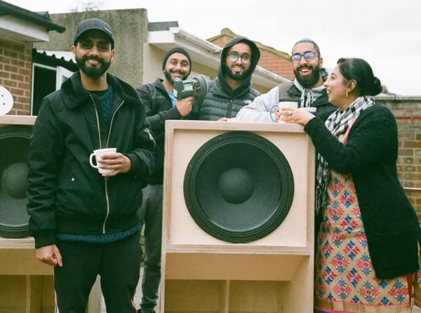 5 members of Southall sound system Vedic Roots pose in front of speakers