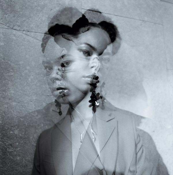 A black and white multiple exposure image of a black woman, with her hair in bunches, facing the camera