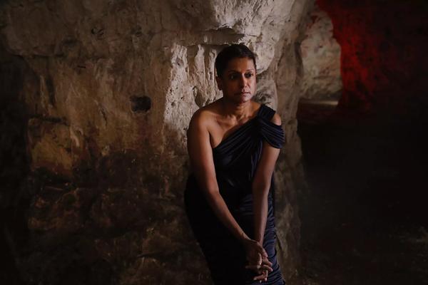 Person wearing a blue off the shoulder dress standing in a cave.