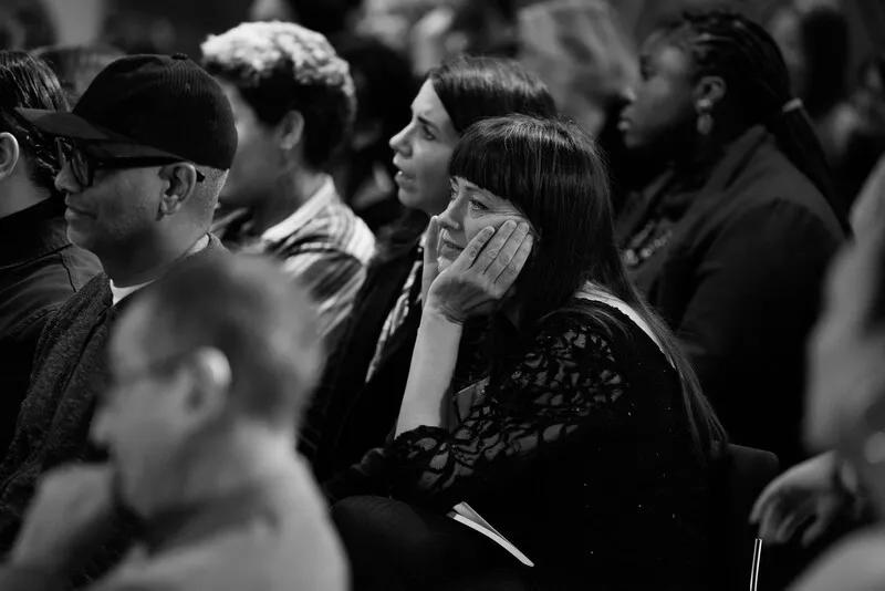 Woman sitting in audience leaning forward and listening.
