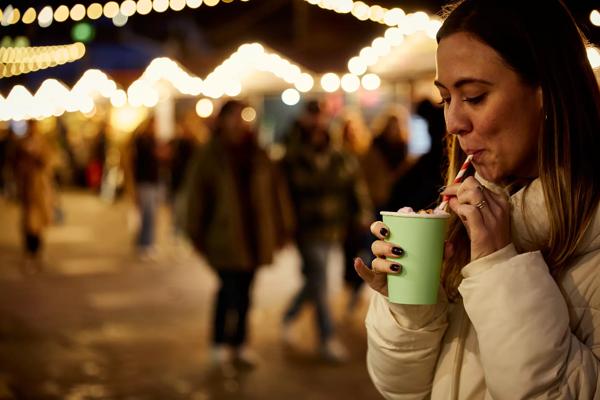Woman in a white puffer coat sipping a hot chocolate with a straw