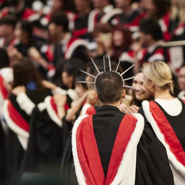 Graduates wearing black gowns with red and white hoods