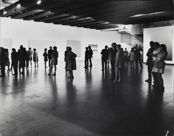 Visitors the Hayward Gallery's 1971 exhibition of the works of Bridget Riley take in the art work.