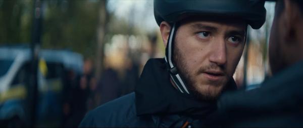 A man in a bike helmet staring intensely at another man